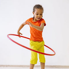 Active child playing with a hula hoop wearing a breathable blank orange t-shirt, showcasing durable fabric for custom kids sports uniforms