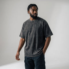 Male model wearing custom dark grey acid wash oversized t-shirt, 250gsm heavyweight cotton streetwear fit.