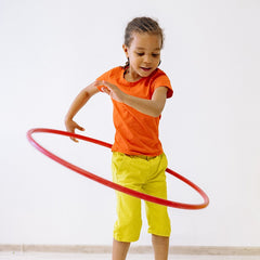 Active child playing with a hula hoop wearing a breathable blank orange t-shirt, showcasing durable fabric for custom kids sports uniforms