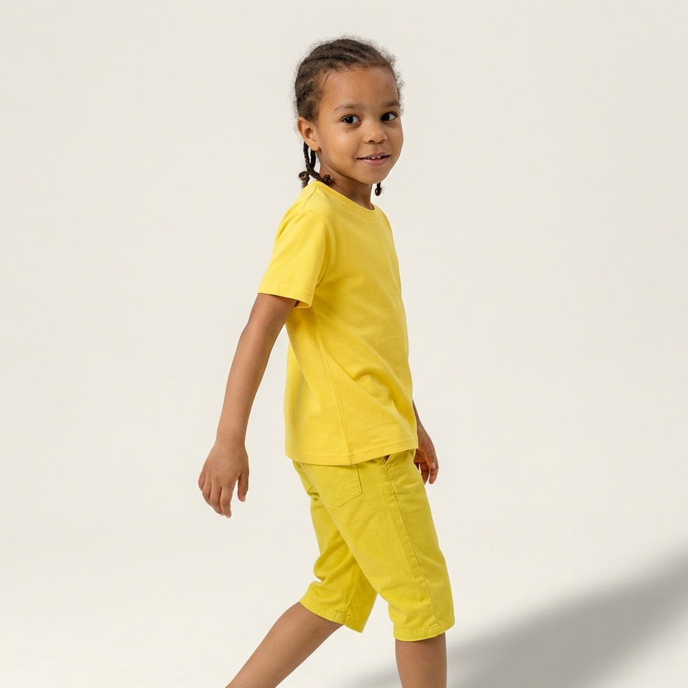 Side profile of a young boy model wearing a plain yellow t-shirt and matching shorts, ideal for custom youth team apparel and personal brand mockups